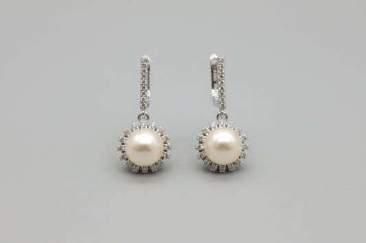 Pair of pearl earrings with silver accents on a gray background